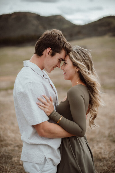 A young couple standing together forehead to forehead at Dawson Butte open space in Colorado. 