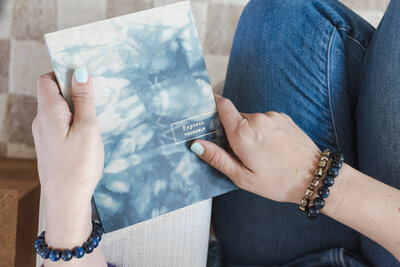 Hand with blue painted nails holding a blue journal