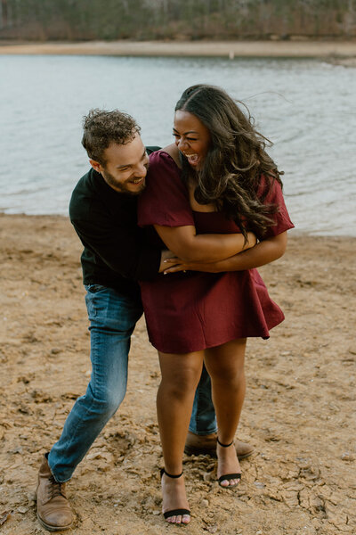 man hugs woman at beach engagement 