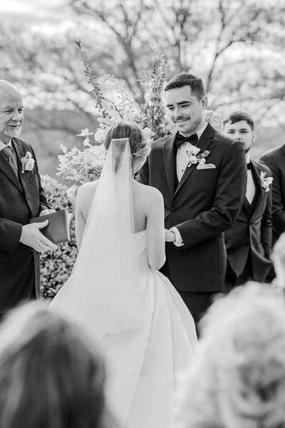 Groom smiling down at the bride while they hold hands during their ceremony, shot on 35mm film