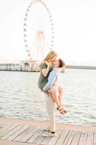 engaged couple kissing on pier