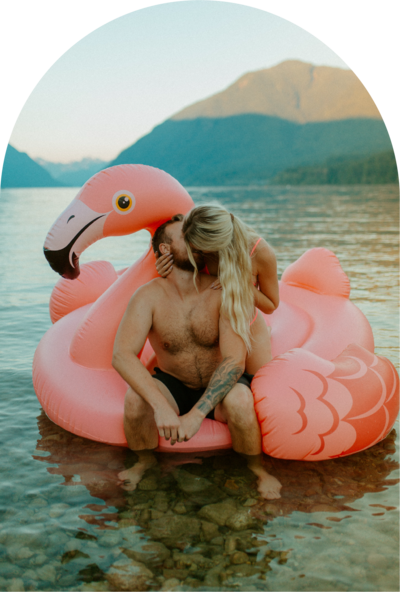 couple kissing sitting on a pink flamingo floatie