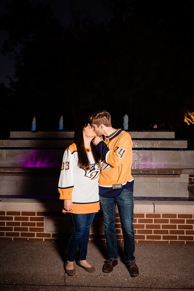 Lipscomb graduates sharing a kiss near the fountains on campus at night