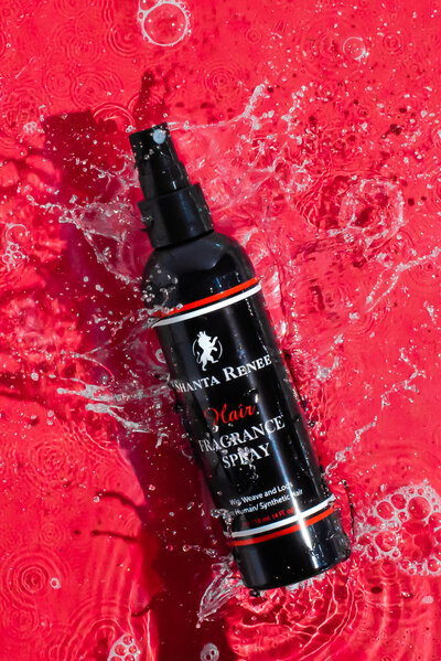 Bottle of haircare product splashing into water with red background