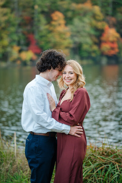 Man nuzzles his beautiful, blonde fiance while she smiles during their engagement session at Vogel State Park in North Georgia. Athens Engagement Photography by Amanda Touchstone