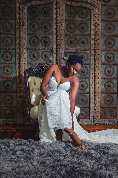 Black bride putting on high heel shoes