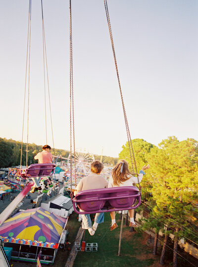 3 siblings swing in a high, twirly fair ride documented by Bailey Feeler