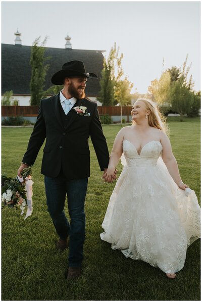 Twin Falls Wedding Photographer | bride and groom walk hand in hand near barn in Twin Falls Idaho