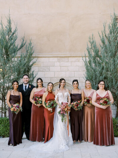 a bride holding a bouquet of overflowing fall flowers on her wedding day at a California vineyard.