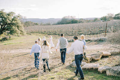 Landscape image of a family all walking together away from the camera in a grassy field