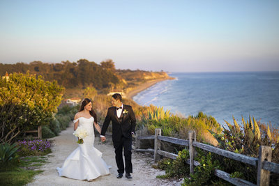 Wedding Photography, bride and groom walking on pathway that overlooks the ocean