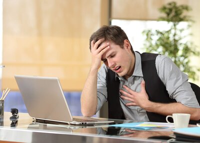 Man looking stressed out looking at laptop