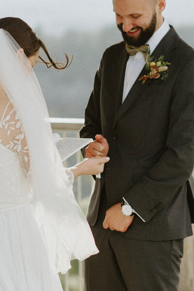 bride and groom pinky promising and laughing during ceremony