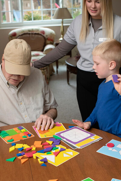 Senior man sitting with great-grandchild while caregiver helps out