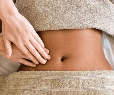 Massage therapist applying light pressure to the abdomen during a lymphatic drainage session.