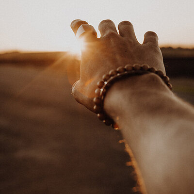 hand reaching toward the setting sun releasing attachments