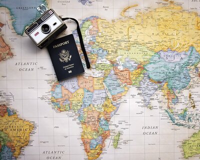 World map background with camera and passport on top