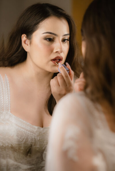 bride put on lipstick in front of mirror at the river view at occoquan wedding