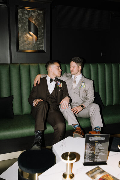 Black and white image of bride and groom sitting on stools at a bar