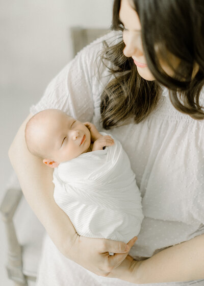 A photo of a mother holding her newborn baby in a Dallas TX photography studio.