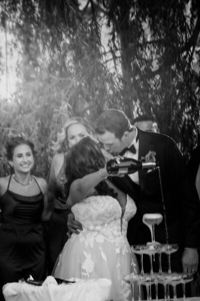 bride and groom spray bottle of champagne to celebrate wedding day