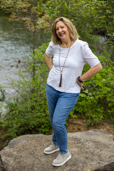 woman with hands on hips on rock in front of water