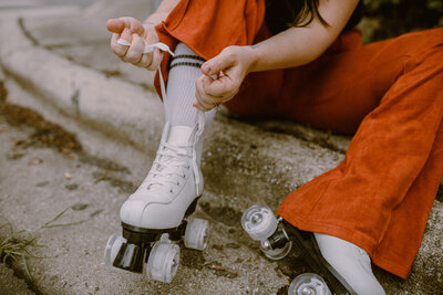 Woman lacing up white roller skates
