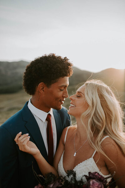 moving GIF of a groom kissing his bride with a mountain view behind