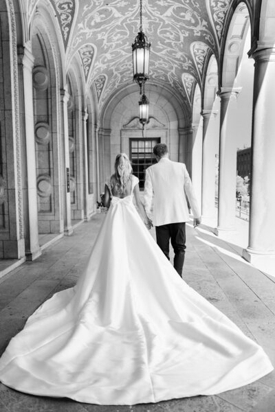 black and white image of a couple holding hands while walking away