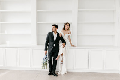 bride and groom standing near bookshelf