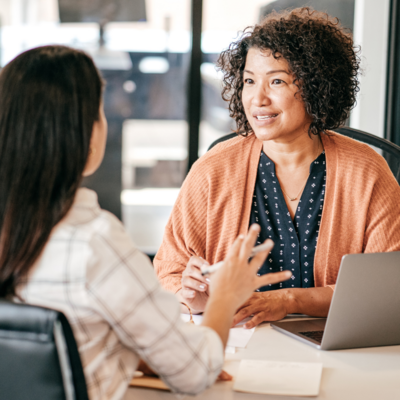 TWO WOMAN HAVING CONVERSATION IN OFFICE NEAR LAPTOP