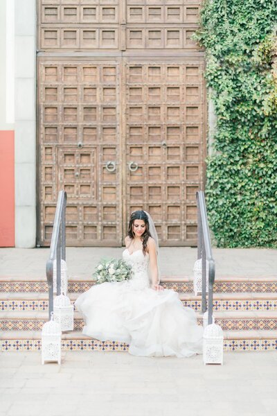 Bride sitting on the steps in front of the large wood doors at the Omni Montelucia in Scottsdale