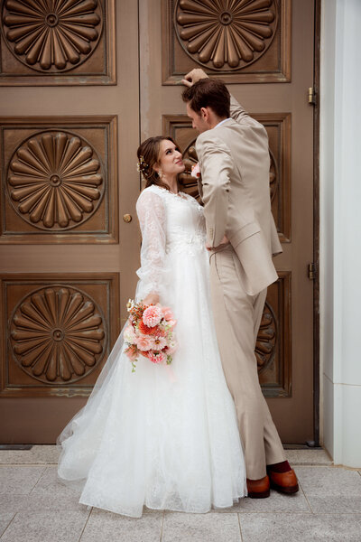 groom leaning over bride against door