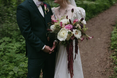 A couple holding a moody bouquet of florals. 