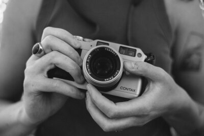 Up close black and white picture of a woman's hands holding a 35mm film camera