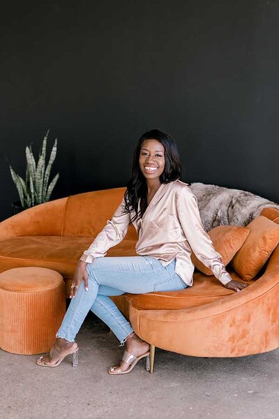 Storytelling Coach Speaker and emcee posing on orange couch