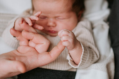 Ein Neugeborenes Baby umfasst den Finger des Vaters mit seinen kleinen Händchen