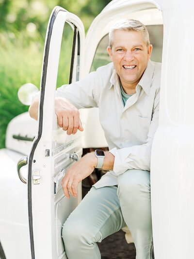 Father sitting in a white 1951 Ford truck with his arm resting on the window.