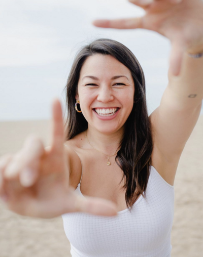 Samantha Okazaki holds her hands up to "frame" the camera and smiles