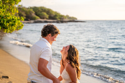 Couple sharing a joyful moment during a sunset proposal at ʻAnaehoʻomalu Bay in Waikoloa, photographed by Hawaii Adventure Portraits, a Big Island proposal photographer