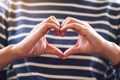 closeup-image-of-a-woman-making-heart-hand-sign-2024-12-05-16-44-55-utc_1