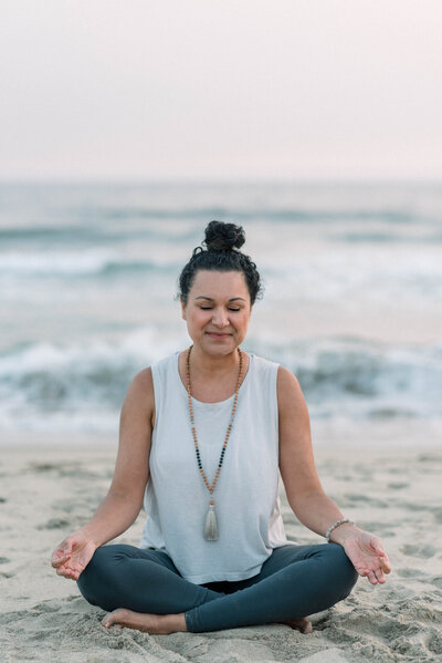 Woman sitting on beach meditating