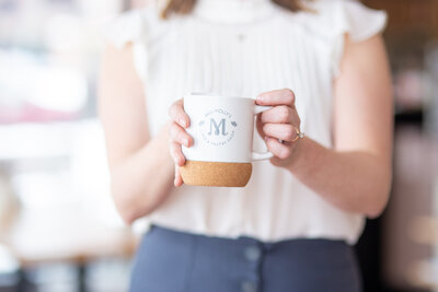 Woman holding a mug - close up of hands on the Cafe branded mug