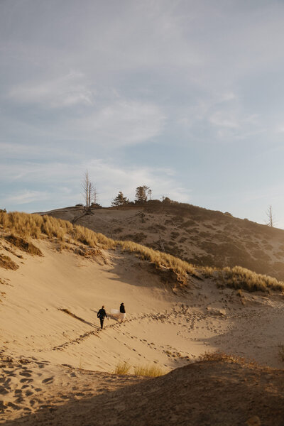 A couple in the distance walking along a sand dune 
