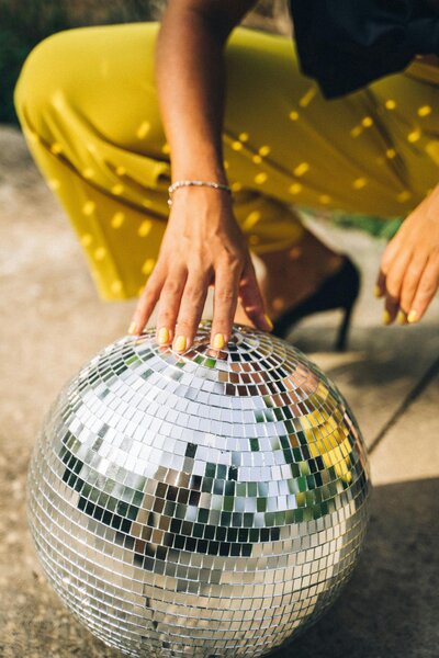 Woman holds a disco ball on the ground still