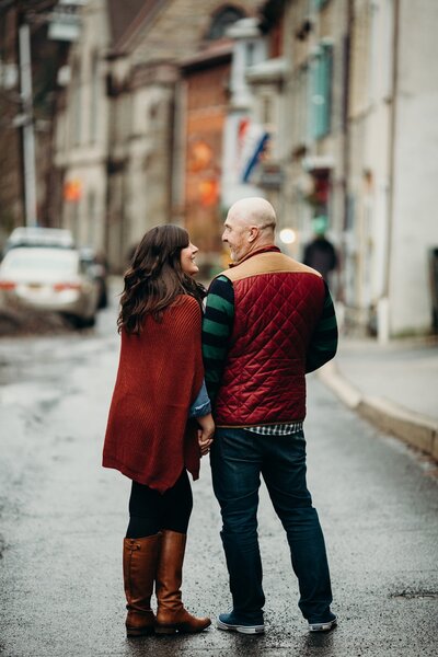 Couple embracing on a city sidewalk during winter engagement session.