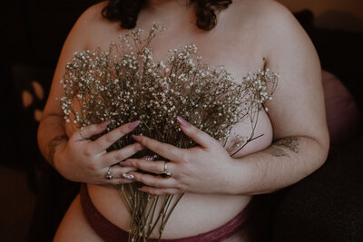 girl holding babys breath as a bra to her chest