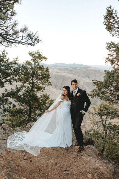 Bride and groom standing on top of a mountain gazing out at the beautiful landscape
