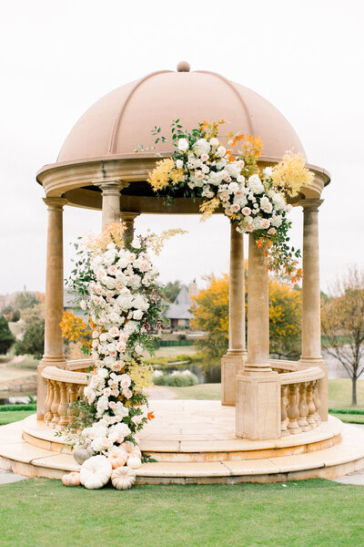 Autumn Oklahoma country club wedding ceremony under a floral gazebo with seasonal blooms and elegant estate style