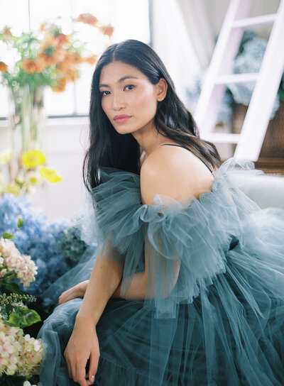 Model in blue tulle dress surrounded by flowers